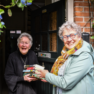 vrouw geeft boeken aan andere vrouw