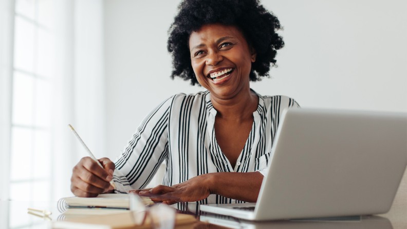 vrouw achter laptop die iets opschrijft